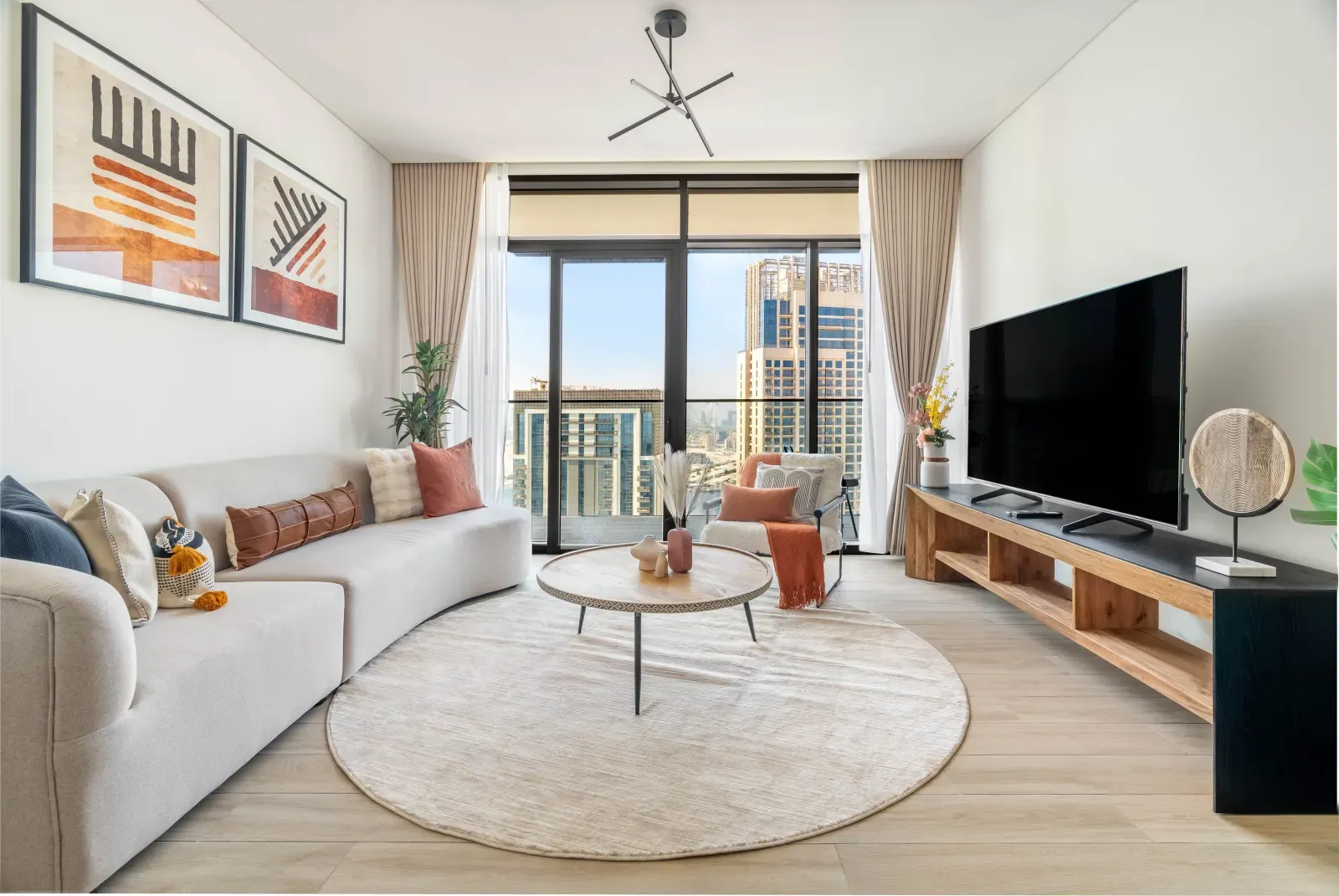 Airy furnished living room in warm neutrals with a sofa, round coffee table and a bright balcony view